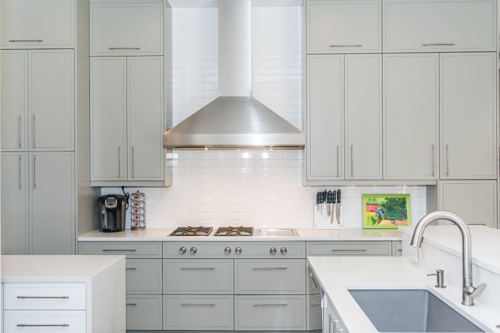 Modern kitchen remodel in Austin with light grey cabinets, white countertops, and silver accents.
