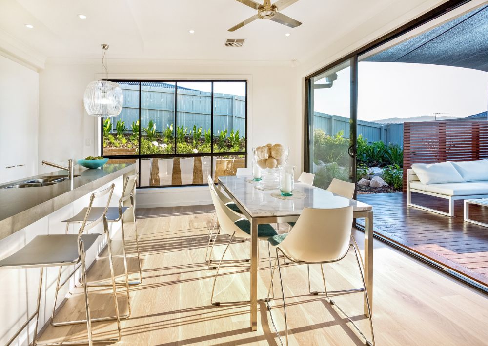 Custom Austin home remodel with a modern dining room, light wood floors, and big windows leading to the back porch.