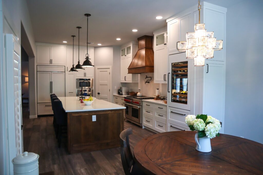 A Remodeled Kitchen with a Dark Stained Wood Island, White Perimeter Cabinets, and White Countertops