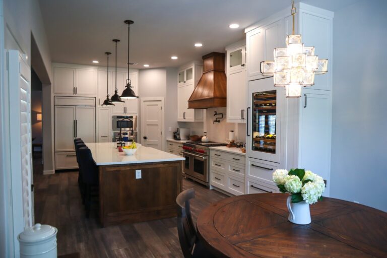 A Remodeled Kitchen with a Dark Stained Wood Island, White Perimeter Cabinets, and White Countertops