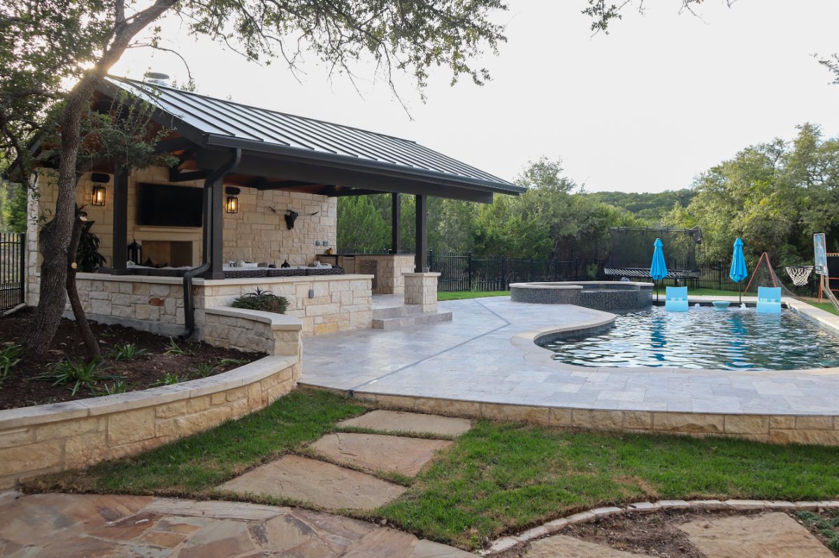 An Outdoor Living Area with a Large Covered Seating Area, a Firepit, a Pool, and a Hot Tub